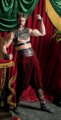 a man in costume standing next to a red curtain