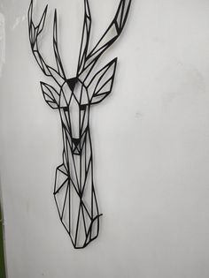 a metal deer head mounted to the side of a wall with geometric lines on it