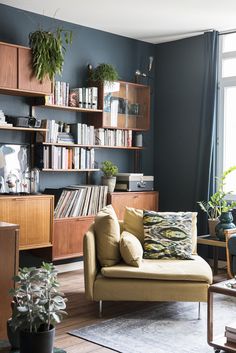 a living room filled with furniture and bookshelves next to a wall mounted book shelf