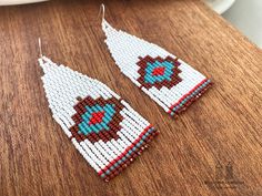 a pair of beaded earrings sitting on top of a wooden table