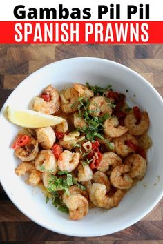 a white bowl filled with shrimp and garnish on top of a wooden table