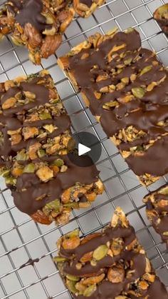 several pieces of chocolate covered granola on a wire rack with nuts and other toppings