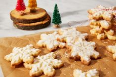 some cookies are on a piece of brown paper with snowflakes and trees in the background