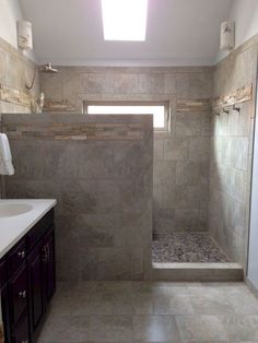 a walk in shower sitting next to a sink under a window on top of a tiled floor