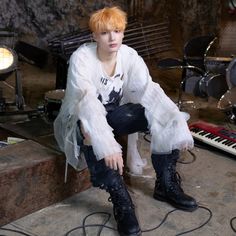 a young man sitting on top of a wooden floor next to a keyboard and musical equipment