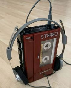 an old stereo with headphones attached to it sitting on the floor next to a pair of headphones