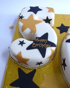 two decorated birthday cakes sitting on top of a gold plate with stars around them and the words happy birthday written on it