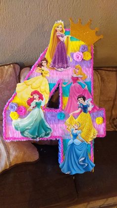 a birthday cake shaped like the number four with princesses on it