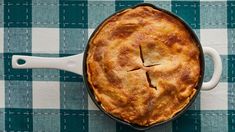 a pie sitting on top of a blue and white table cloth next to a knife