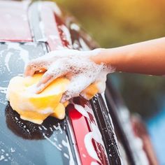 a person washing the window of a car with a sponge and microfiber cloth