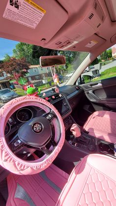 the interior of a pink car with stuffed animals on the dashboard and steering wheel,