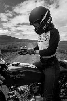 black and white photograph of a person on a motorcycle wearing a helmet with the words honda written on it