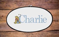 a cross stitch name sign with a winnie the pooh bear holding a teddy bear