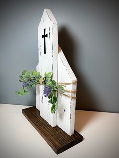 a small wooden church with a cross on it's side and flowers in the front