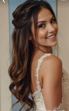 a woman with long brown hair wearing a white dress and smiling at the camera while standing in front of a mirror