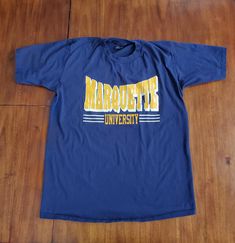 "In Very Good To Great Vintage Condition. Graphics have some normal vintage fading but there are no flaws to note. See Extra Measurements to insure a good fit:  Top to Bottom: 30 & 1/2\"  Pit to Pit: 22 & 1/2\"  Sleeve: 8 & 1/2\"" Retro Blue T-shirt For College, 90s Blue Sports T-shirt, 90s Blue T-shirt For College, 90s Style Blue T-shirt For College, Marquette University, Golden Eagles, University Tshirt, Good To Great, Dark Blue