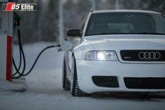 the front end of a white car with an electric charger attached to it's hood