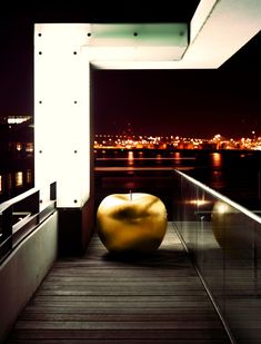 a large yellow apple sitting on top of a wooden floor next to a building at night