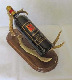 a bottle of wine sitting on top of a wooden stand with antlers around it