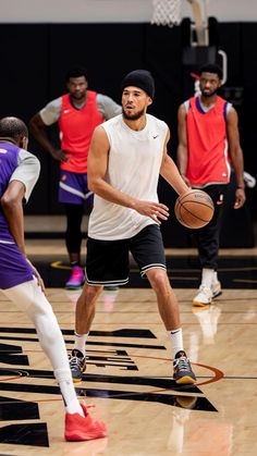 several men playing basketball on a court with one holding a ball in his hand and the other dribble