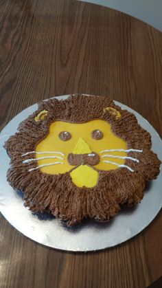 a lion cake is sitting on a plate with brown icing and white frosting