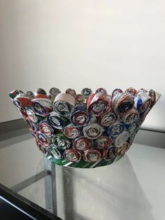 a bowl made out of cans sitting on top of a glass table