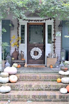 front porch decorated for fall with pumpkins and wreath