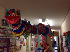 a room filled with lots of colorful balloons and paper hats hanging from the ceiling above them