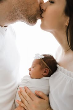 a man and woman holding a baby in their arms