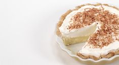 a white plate topped with a pie covered in whipped cream and toasted crumbs