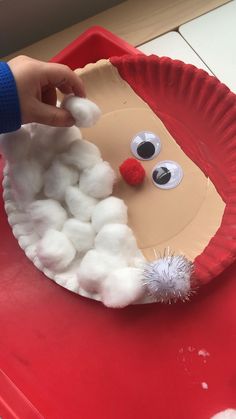 a paper plate that has some cotton balls in it and a reindeer face on it