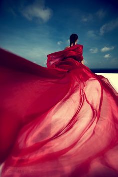 a woman in a long red dress on the beach