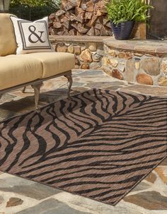 a brown and black rug sitting on top of a stone floor next to a couch