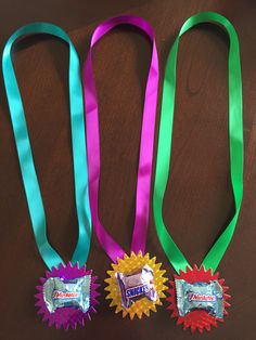 three ribbons with candy bars on them sitting next to each other in front of a wooden table