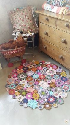 a teddy bear is sitting on the floor next to a crocheted rug