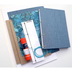 an assortment of crafting supplies are laid out on top of each other, including notebooks and paper