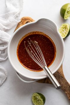 a white bowl filled with sauce next to limes