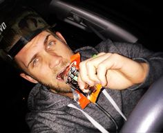 a man holding an orange drink in his hand while sitting in the back seat of a car