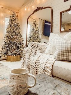 a living room filled with furniture and a christmas tree in front of a large mirror