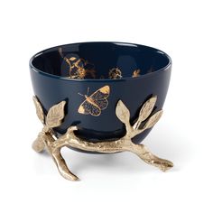 a blue bowl with gold leaves and butterflies on the rim, sitting on a white surface