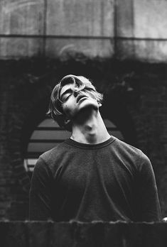 a man standing in front of a brick building with his eyes closed and looking up