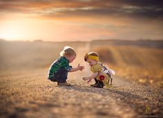 two young children playing in the middle of a dirt road with sun setting behind them