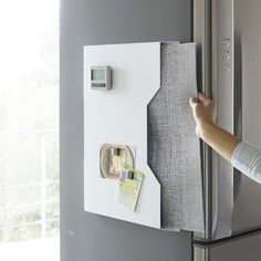 the refrigerator door is open with magnets on it and someone's hand reaching for something