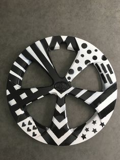 a black and white circular object on the ground with dots, stars and stripes painted on it