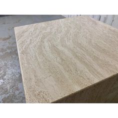 a close up of a wooden table top in a room with concrete flooring and walls