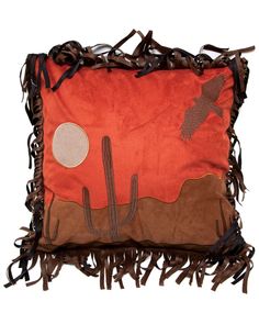 an orange pillow with brown fringes and a bird on it