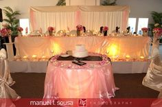 a wedding cake sitting on top of a table covered in pink and white cloths