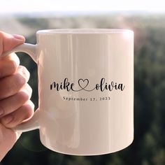 a person holding a white coffee mug with the word mike and julia on it in black ink