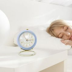 a woman laying in bed with an alarm clock on the side table next to her