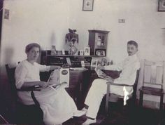 an old black and white photo of two people sitting in chairs